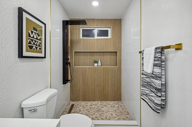 full bath with a textured wall, a stall shower, and toilet