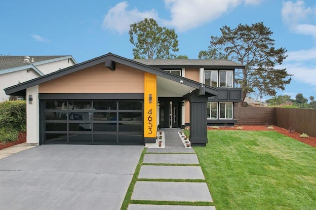 view of front of home with a garage, concrete driveway, fence, and a front lawn