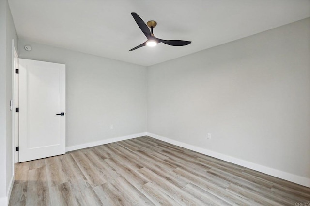 empty room with ceiling fan, light wood-style flooring, and baseboards