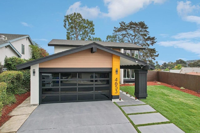 view of front facade with a garage, concrete driveway, a front lawn, and fence