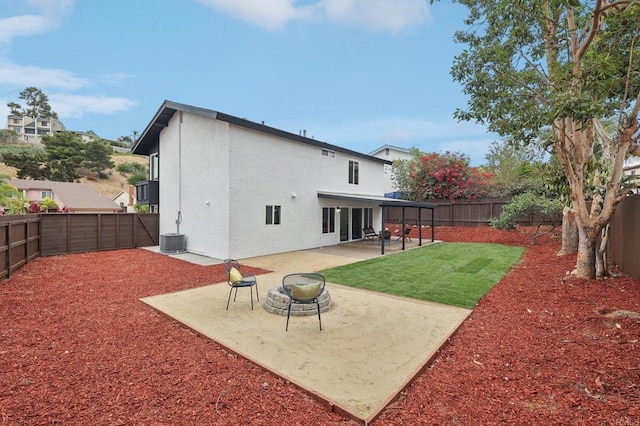 back of house featuring stucco siding, a lawn, an outdoor fire pit, a patio area, and a fenced backyard