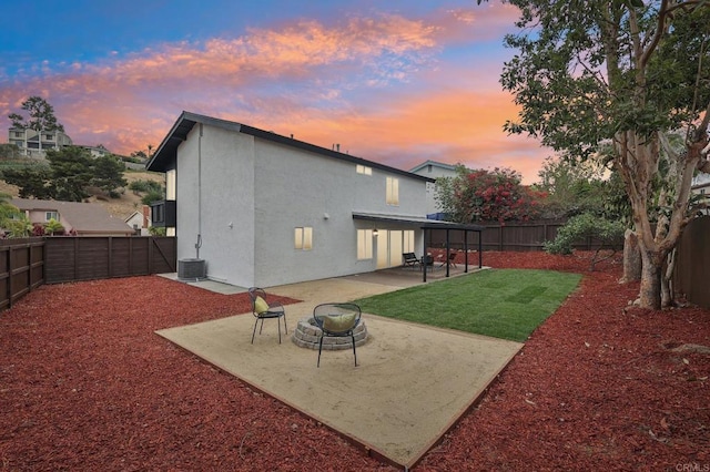 rear view of house with a patio, stucco siding, a lawn, an outdoor fire pit, and a fenced backyard