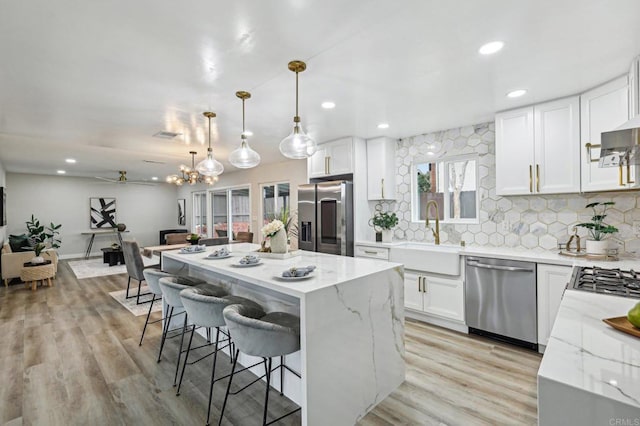 kitchen with stainless steel appliances, a sink, a center island, and white cabinets