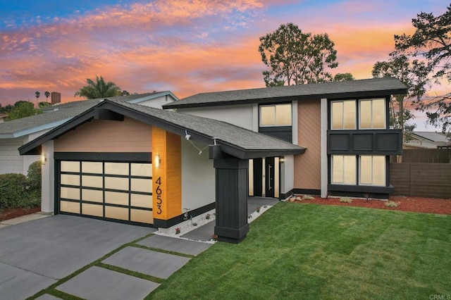 view of front facade featuring a garage, fence, a lawn, and concrete driveway