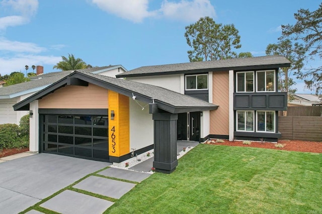 view of front of property with a shingled roof, concrete driveway, fence, a garage, and a front lawn