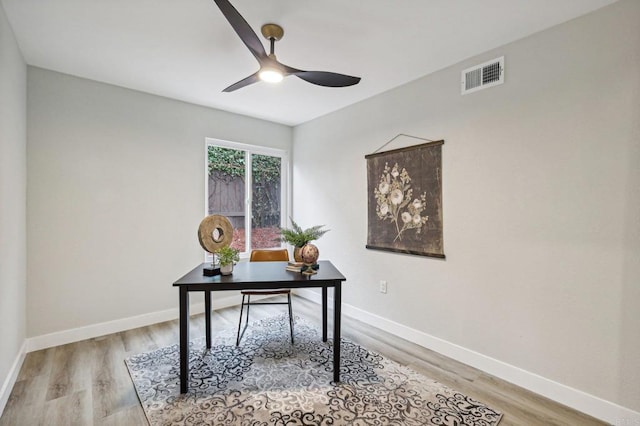 office featuring light wood finished floors, ceiling fan, visible vents, and baseboards