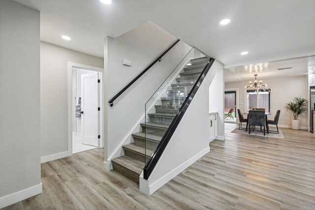 stairway with a chandelier, recessed lighting, wood finished floors, and baseboards