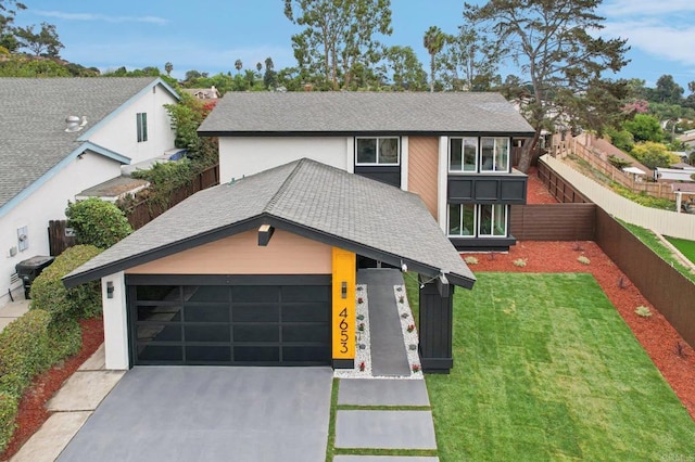 view of front of property with a garage, a shingled roof, concrete driveway, fence, and a front yard