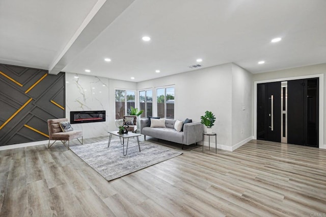 living area featuring light wood-style floors, a premium fireplace, visible vents, and recessed lighting