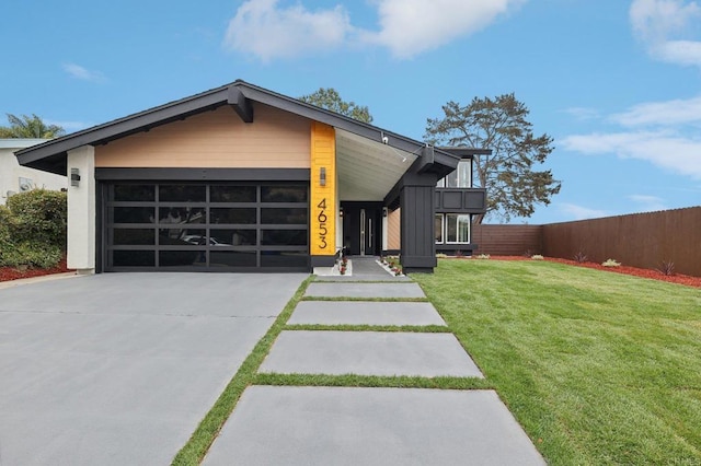 view of front of home featuring an attached garage, fence, a front lawn, and concrete driveway