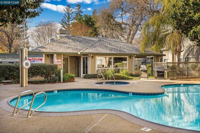 view of swimming pool with a grill and a hot tub