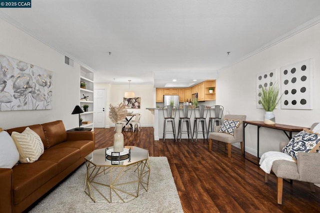 living room with crown molding, dark hardwood / wood-style flooring, and built in shelves