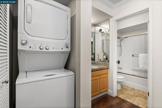 laundry room with ornamental molding and stacked washing maching and dryer