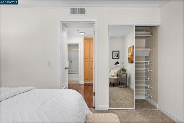 carpeted bedroom with crown molding and a closet