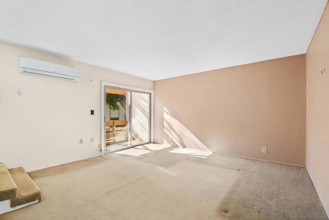 unfurnished room with carpet floors, a wall unit AC, and a textured ceiling