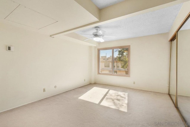 unfurnished bedroom with ceiling fan, carpet floors, a closet, and a textured ceiling