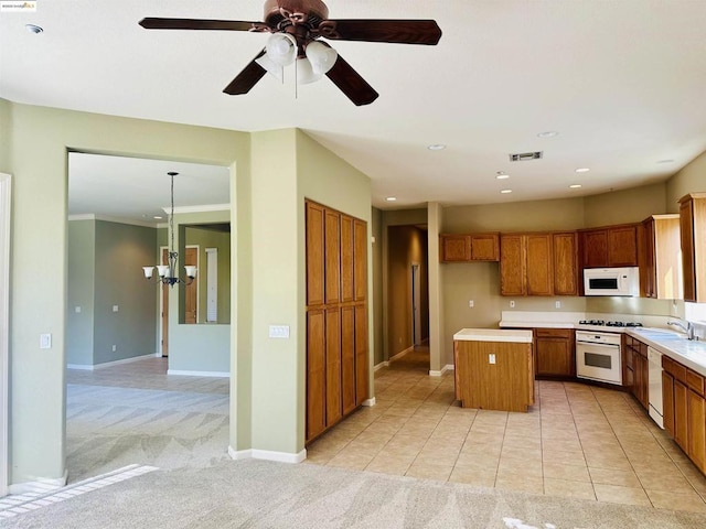 kitchen with pendant lighting, sink, white appliances, a kitchen island, and light carpet