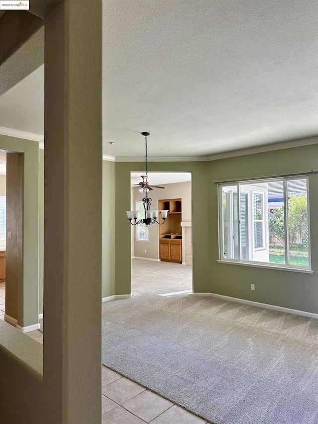 carpeted empty room with ornamental molding, a textured ceiling, and a chandelier