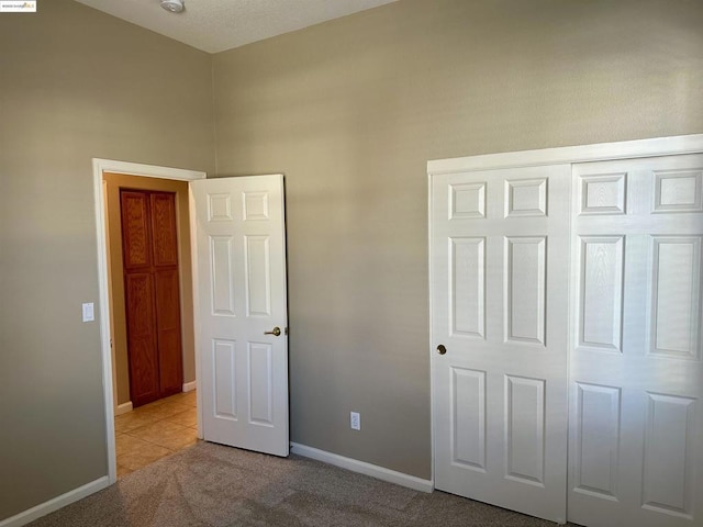 unfurnished bedroom featuring light colored carpet and a closet