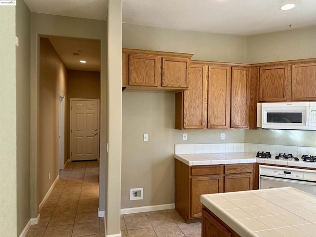 kitchen with white appliances, tile counters, and light tile patterned floors