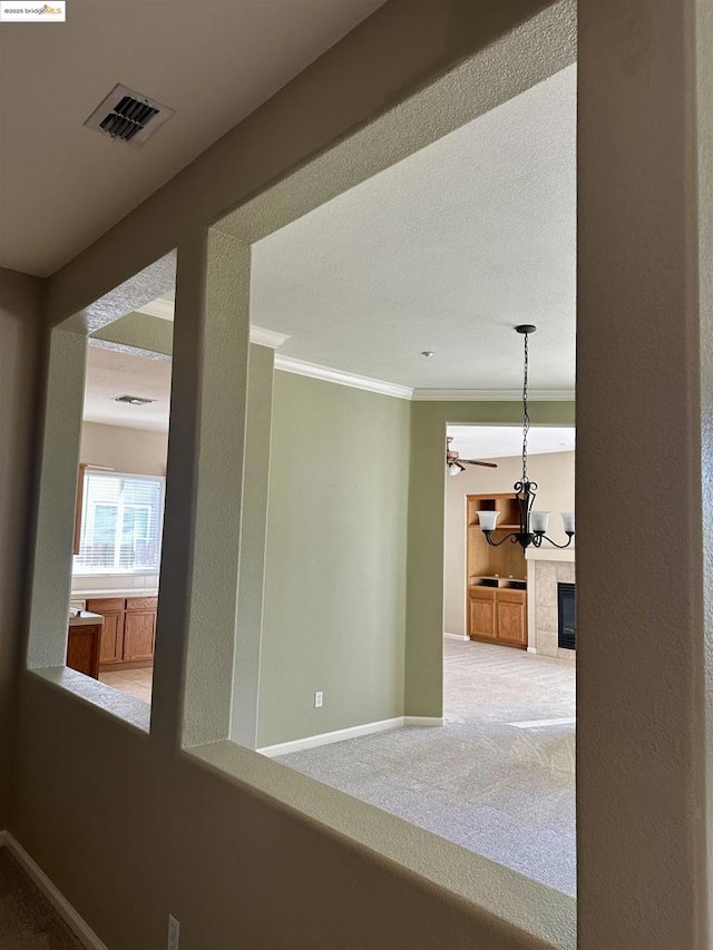 hallway with crown molding, a chandelier, and carpet flooring