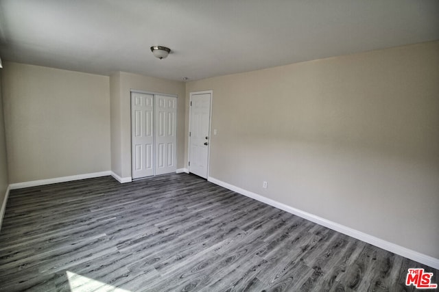 unfurnished bedroom featuring dark hardwood / wood-style flooring and a closet