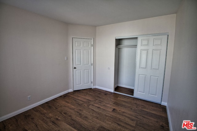 unfurnished bedroom with dark wood-type flooring and a closet