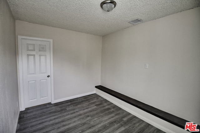 empty room featuring dark hardwood / wood-style floors and a textured ceiling