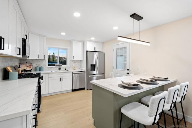 kitchen with sink, white cabinetry, decorative light fixtures, appliances with stainless steel finishes, and backsplash