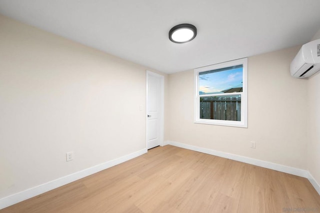 spare room featuring an AC wall unit and light wood-type flooring