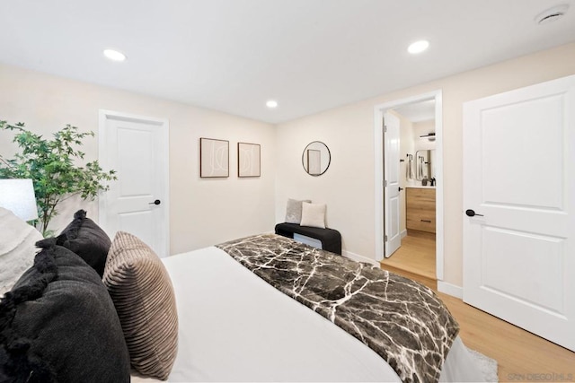 bedroom with ensuite bathroom and light hardwood / wood-style floors