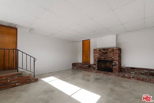 unfurnished living room with a paneled ceiling, a fireplace, and concrete flooring