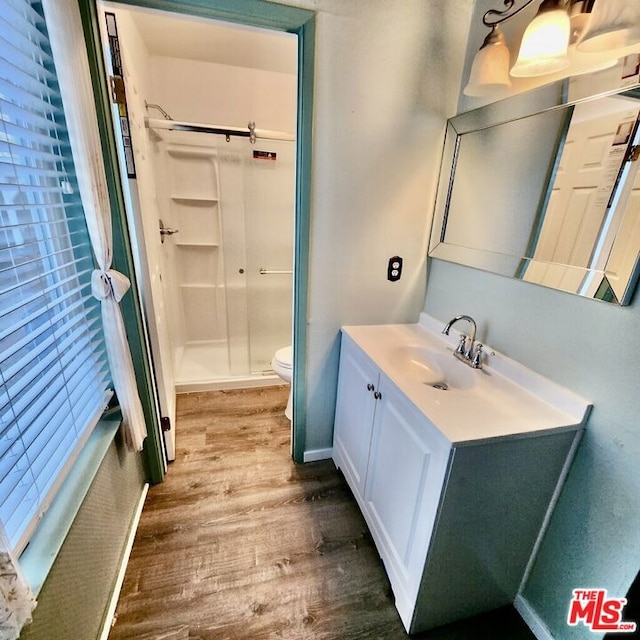 bathroom featuring hardwood / wood-style flooring, vanity, a shower with door, and toilet