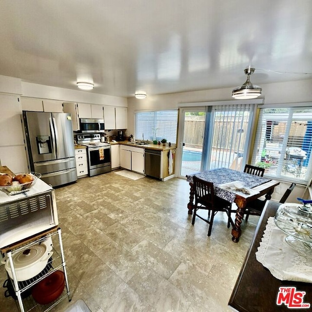 kitchen featuring hanging light fixtures, appliances with stainless steel finishes, plenty of natural light, and white cabinets