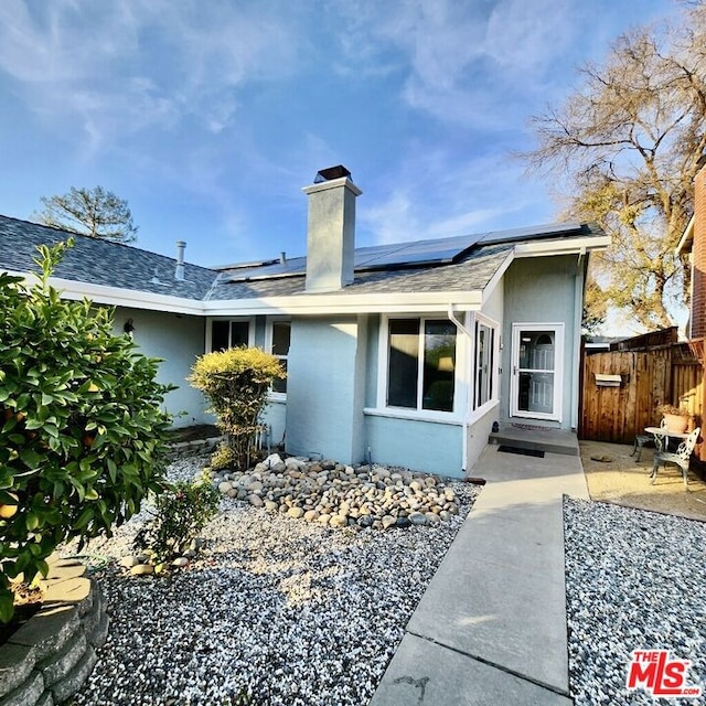 rear view of property with solar panels and a patio area