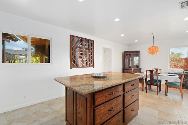 kitchen featuring plenty of natural light, a center island, pendant lighting, and light stone counters