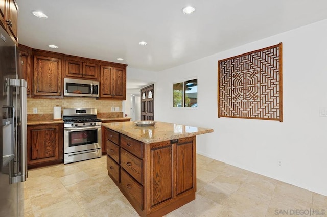 kitchen with tasteful backsplash, light stone countertops, stainless steel appliances, and a kitchen island