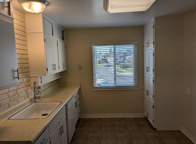 kitchen featuring white dishwasher, sink, decorative backsplash, and white cabinets