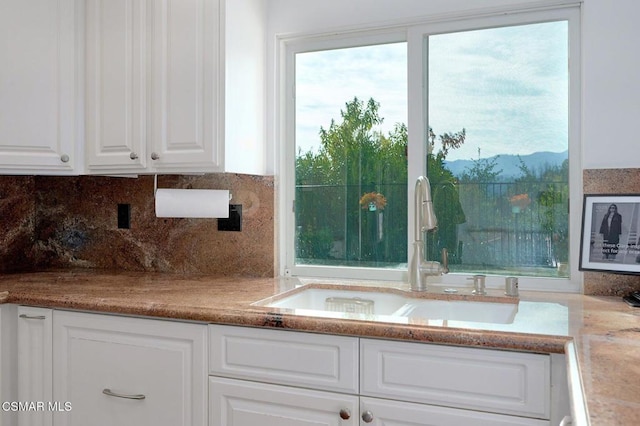 room details featuring tasteful backsplash, sink, and white cabinets