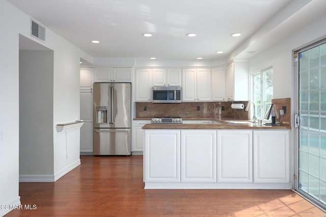 kitchen featuring appliances with stainless steel finishes, dark hardwood / wood-style floors, kitchen peninsula, and white cabinets