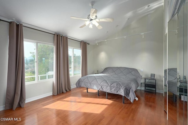 bedroom with hardwood / wood-style flooring, ceiling fan, and track lighting