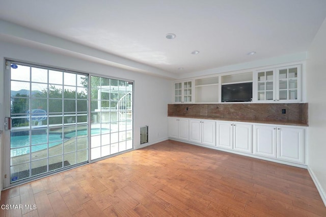 kitchen with a healthy amount of sunlight, white cabinets, and light wood-type flooring