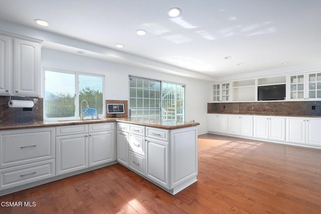 kitchen with sink, white cabinetry, dark hardwood / wood-style floors, tasteful backsplash, and kitchen peninsula