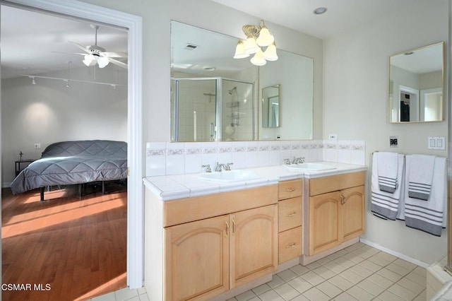 bathroom with ceiling fan with notable chandelier, decorative backsplash, vanity, an enclosed shower, and tile patterned floors