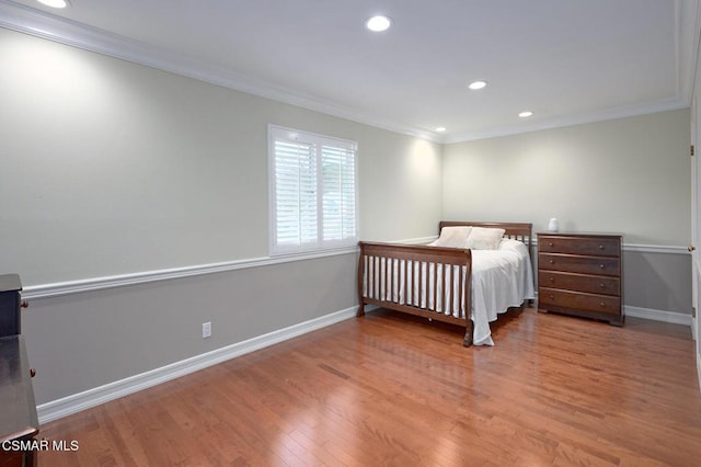 bedroom with ornamental molding and hardwood / wood-style floors