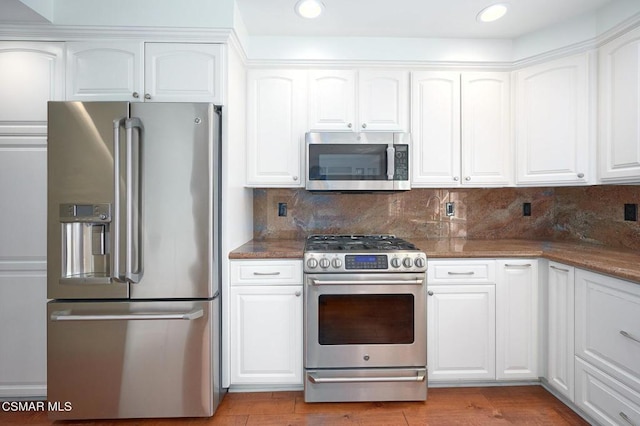 kitchen with dark stone counters, white cabinets, and appliances with stainless steel finishes