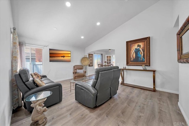 living area with arched walkways, a healthy amount of sunlight, baseboards, and wood finished floors