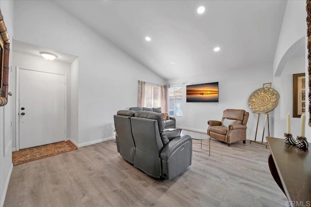 living area featuring wood finished floors, baseboards, recessed lighting, arched walkways, and vaulted ceiling