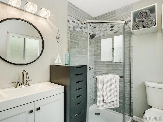 bathroom featuring vanity, a shower with door, and toilet