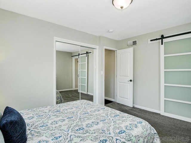 bedroom with dark colored carpet, a barn door, and a closet